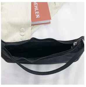 Détail de sac porté épaule hobo en nylon noir, fermeture zippée et design.