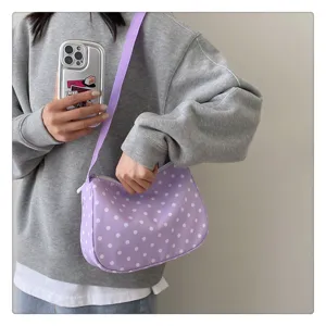 Close-up detail van een trendy paarse nylon schoudertas met polkadots in casual stijl gedragen.