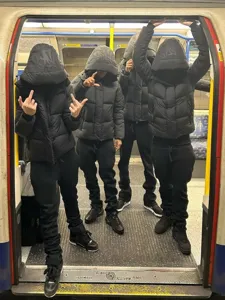 Black hooded padded puffer jacket with matching joggers, trendy street style outfit.