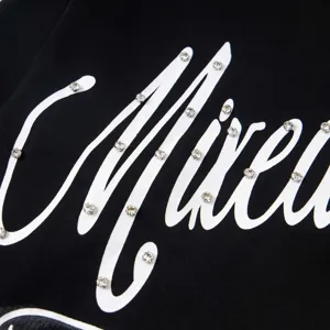 Gros plan très détaillé sur un t-shirt noir à manches longues avec des lettres en strass.