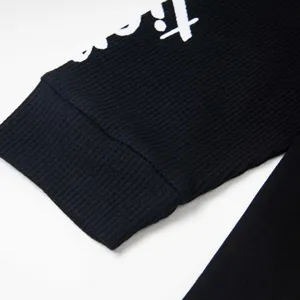 Vue détaillée de la manche de t-shirt à manches longues côtelée noire avec texte imprimé.