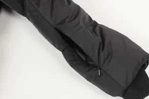 Black functional puffer jacket sleeve detail with zipper pocket and ribbed cuff for street style.