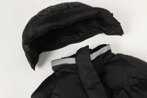 Close-up detail of a black winter puffer jacket with a detachable hood and reflective trim.