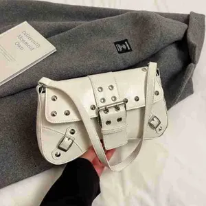 Sac à bandoulière style moto blanc pour femme, design tendance avec clous et boucles.