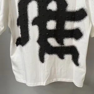 Casual white short sleeve t-shirt featuring a black studded graphic print for streetwear.