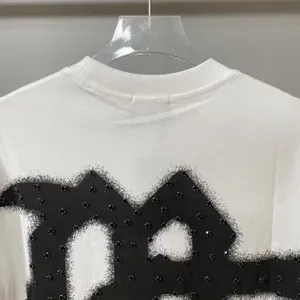 Detail shot of white short sleeve t-shirt with black rhinestone graphic and crew neck styling.