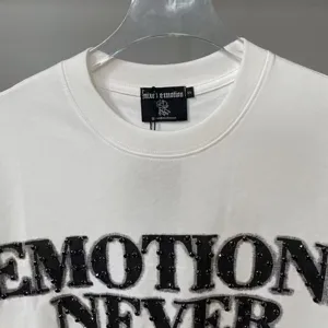Close-up detail of white short sleeve t-shirt featuring rhinestone emotion letter print design.
