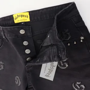 Black denim jeans with gothic embroidery, metal buttons, and branded label for streetwear fashion.