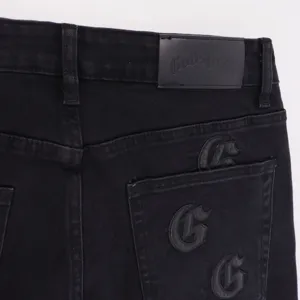 Black high street straight leg jeans detail shot with leather waistband patch and embroidery.