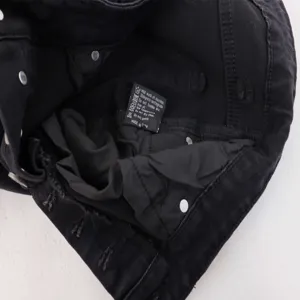 Black straight leg denim jeans detail view with washing care label instructions inside.