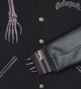 Close-up of black streetwear varsity jacket with skeleton embroidery and metal buttons.