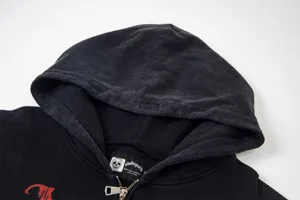 Washed black cotton hoodie with skull logo and metal zipper detail for streetwear fashion.
