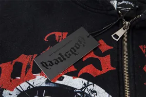 Close-up detail of black washed hoodie with metal zipper, brand hang tag and vintage print.