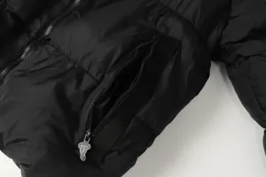 Detailed view of black streetwear puffer jacket featuring zipper pocket and custom hardware.