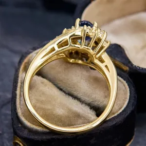 Detailed close-up of a vintage-style gold ring featuring a deep blue center gemstone and accents.