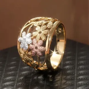 Vista de detalle de anillo floral en oro tricolor, con delicadas flores huecas en estilo pastoral.