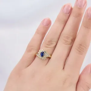 Detailed view of a vintage oval blue sapphire ring with sparkling rhinestones in gold tone.