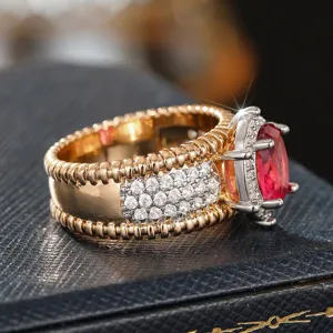 Exquisito anillo de metal bicolor texturizado con piedra roja vibrante y circonitas.