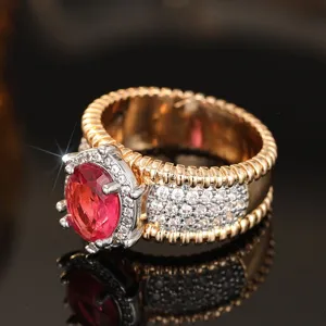 Vista detallada de un anillo vintage de metal bicolor con piedra roja y circonitas.