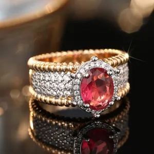 Exquisito anillo de metal bicolor con piedra preciosa roja ovalada y detalles de diamantes.