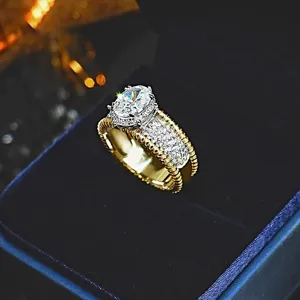 Anillo ancho bicolor de lujo con piedra central ovalada y bordes perlados delicados.