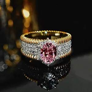 Anillo de metal bicolor con piedra rosa ovalada incrustada y brillantes cristales.