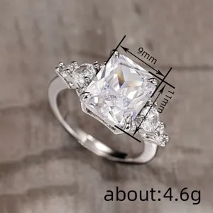 Primer plano detallado del elegante anillo de circonita talla esmeralda con piedras laterales.