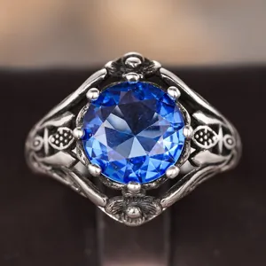 Detailed close-up of a vintage blue gemstone ring featuring an ornate antique silver band design.
