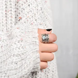 Vintage silver ring detail shot, retro leaf carved band with imitation moonstone, cozy knit style.