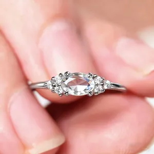 Bague pour femme style coréen minimaliste avec élégante pierre ovale et détails de pierres latérales.
