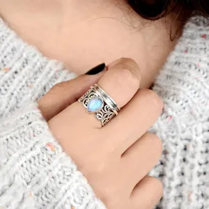 Primer plano de anillo spinner vintage de plata con piedra de luna en gota y filigrana.