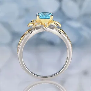 Stunning two-tone sunflower ring with sparkling light blue gemstone and delicate pavé diamond accents.