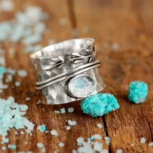 Vintage silver spinner ring detail shot, retro leaf engraved design with simulated moonstone.