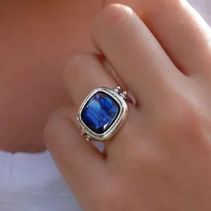 Anillo de plata vintage primer plano con gema azul cuadrada en detalle de modelo de mano.