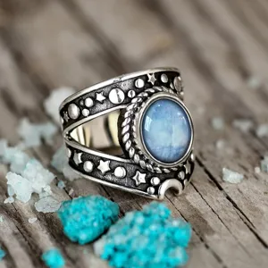 Primer plano detallado de anillo de plata estilo punk vintage con piedra azul y estrellas.