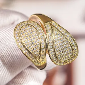 Primo piano che mostra i dettagli in zircone pavé a doppia goccia dell'anello di modo dorato.