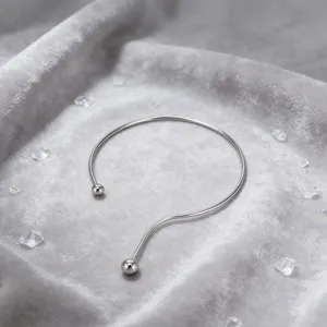 Closeup detail of minimalist stainless steel open collar necklace with dual balls on velvet.