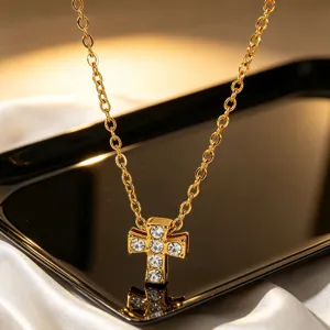 Detalle de un collar con colgante de cruz de acero inoxidable bañado en oro y estrás.