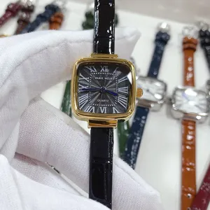 Close-up of square quartz watch dial with Roman numerals and black leather strap.