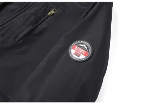 Men's black casual outdoor jacket detail showing sleeve badge and zipper pocket design.