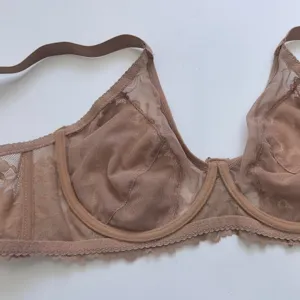 Detail shot of nude lace unlined underwire bra, sheer mesh fabric and delicate floral trim.