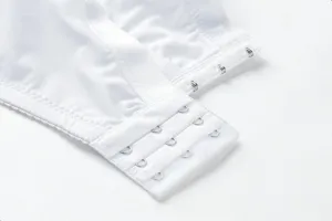 Close-up detail of women's white bra back closure with secure hooks and soft fabric.