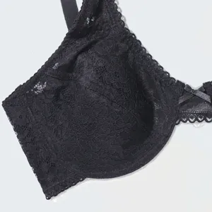 Close-up detail of black lace bra cup, featuring delicate floral pattern and bow accent.