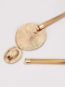 Close-up detail of women gold elastic metal waist belt with sunburst buckle ornament.