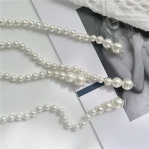 Close-up detail of elegant graduated white pearl waist chain, showing fine beads and metal clasp.
