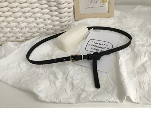 Minimalist black thin belt for women, chic metal buckle waist accessory for jeans and trousers.