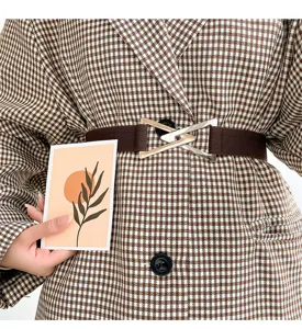 Close-up detail of a brown elastic coat waist belt with a chic metal triangle buckle.