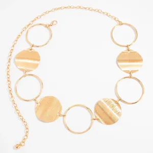 Close-up detail of golden metal chain belt, featuring alternating rings and textured discs.