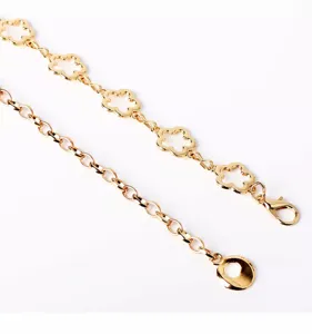 Gold metal flower waist chain detail shot, stylish hollow clover decorative belt for dresses.