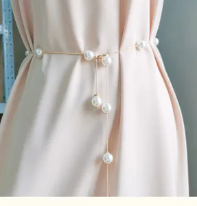 Gedetailleerd overzicht van parelketting taille riem accessoire op elegante zomerse jurk